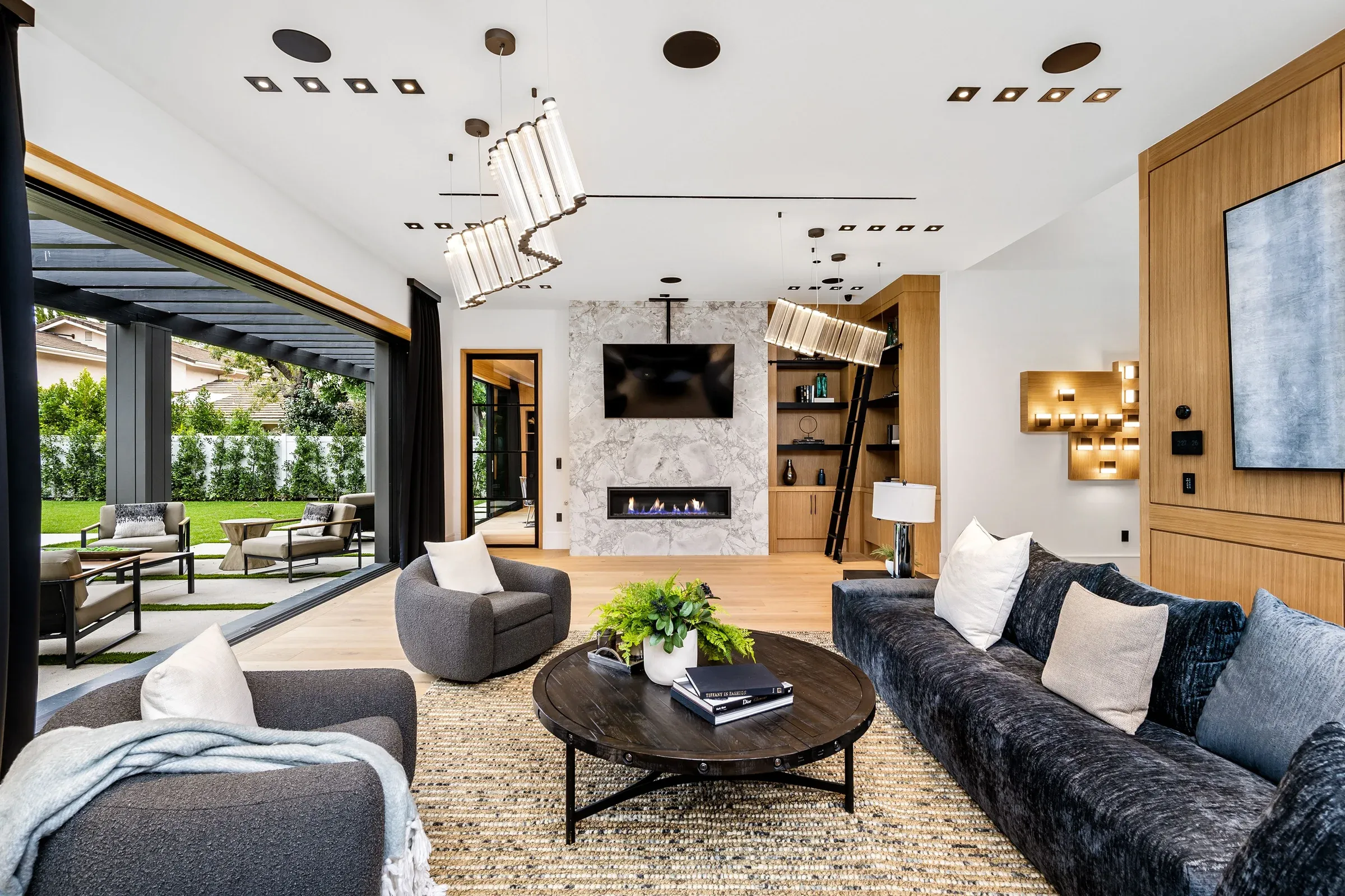 Helles Wohnzimmer mit Sofas, Kamin und offenem Blick in den Garten